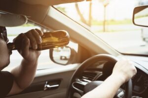 man driving car in NYC while drinking a beer