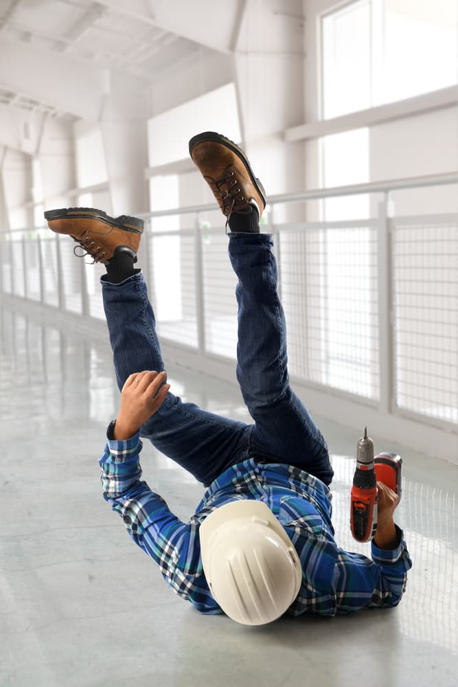 Hispanic worker falling on their back inside a building hallway.