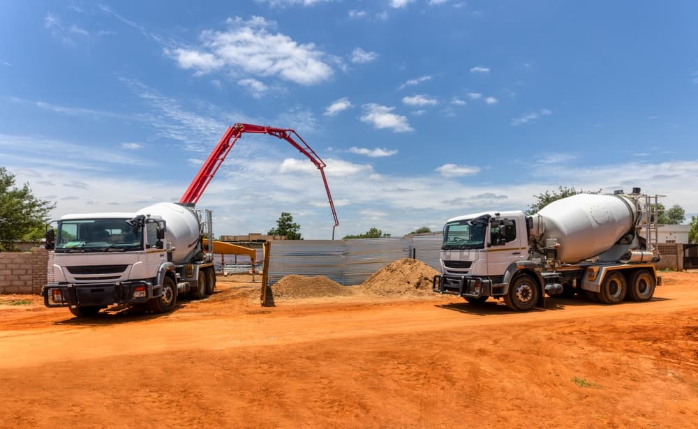 A concrete mixer truck and a boom pump operating at a construction site.






