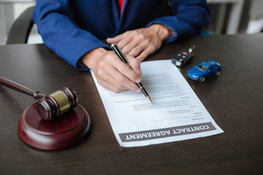 A lawyer working at a table in a courtroom, with a concept of car auctions and fair legal processes in the context of selling a vehicle.