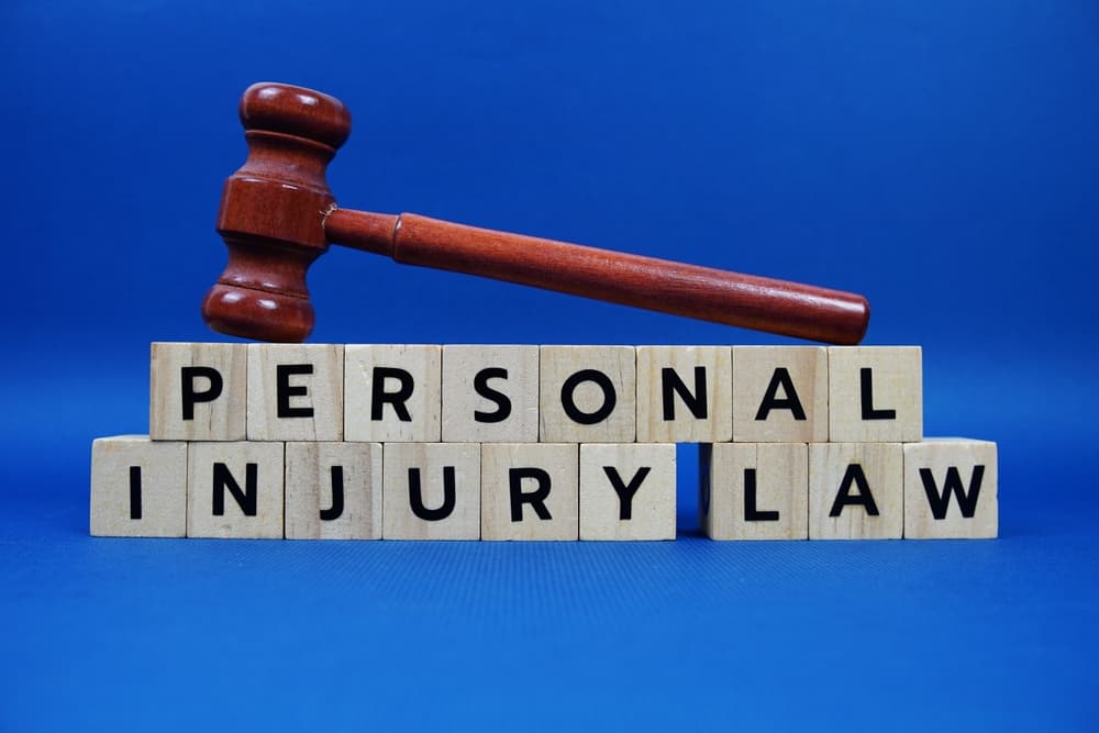 Wooden alphabet blocks spelling "Personal Injury Law" with a gavel on a blue background.






