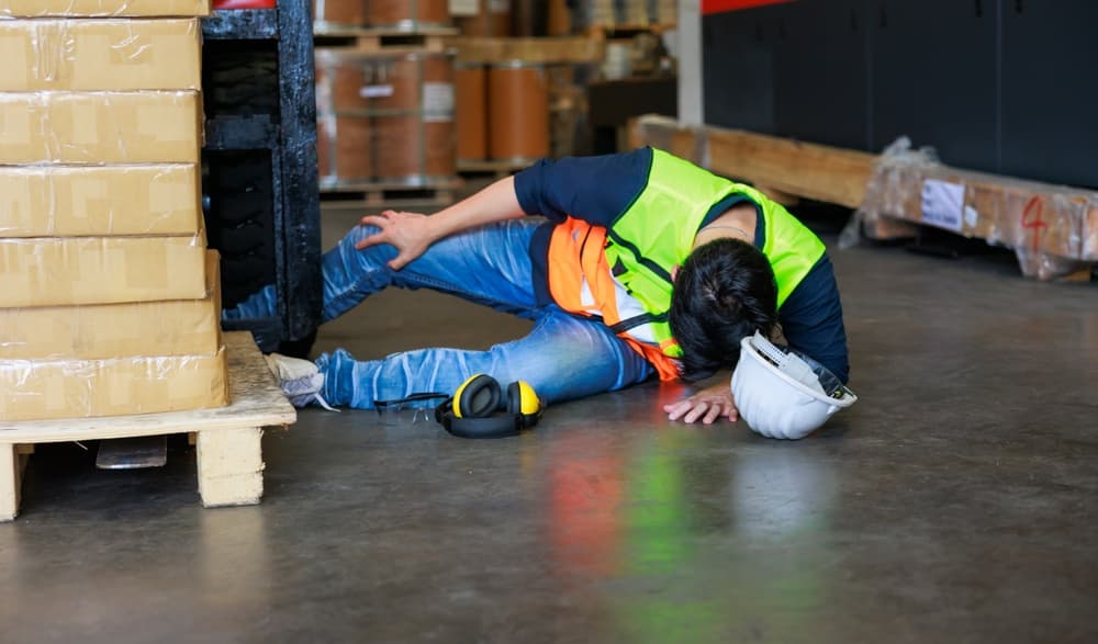 First aid and safety first concept: A warehouse worker lies on the floor after an accident in a factory. Professional engineering team responds to the workplace emergency.







