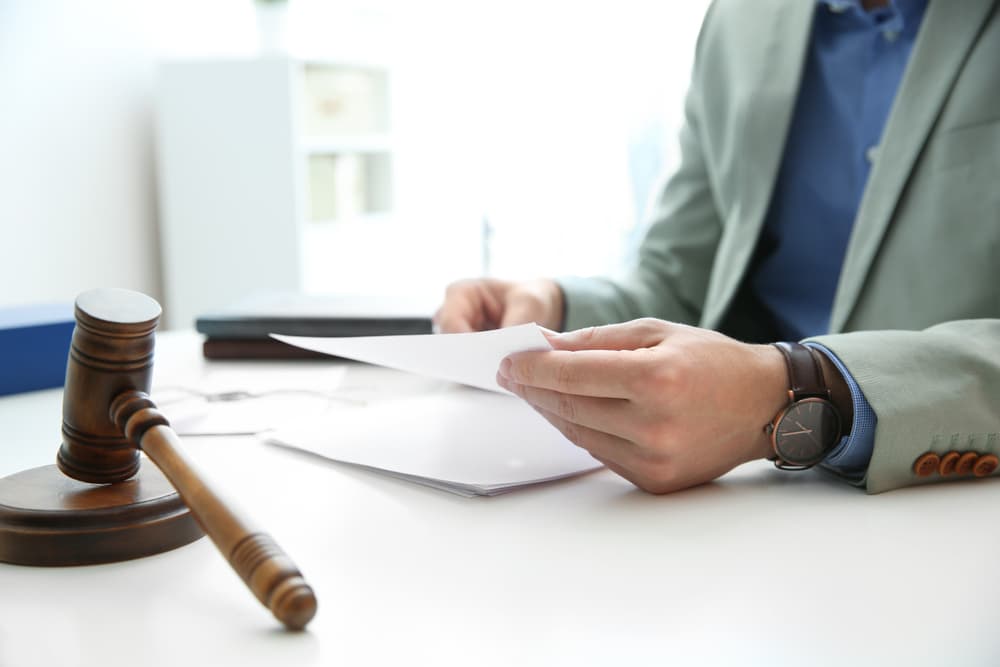 Close-up of a notary working with documents and a judge's gavel on the table, symbolizing law and justice.